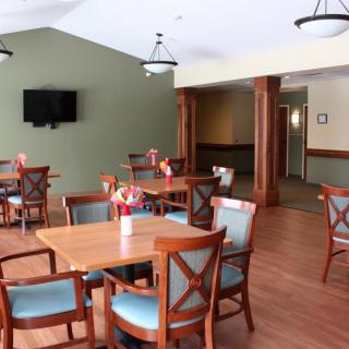 A cozy dining area with wooden tables and chairs, featuring a wall-mounted TV and decorative elements.