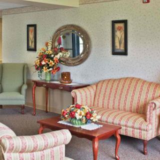 A cozy living room featuring striped sofas, armchairs, floral decor, and elegant wall art.