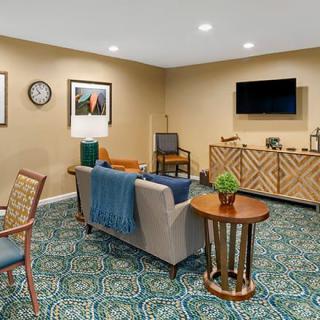 A cozy living room with a sofa, television, and coffee table, featuring elegant decor and artwork on the walls.