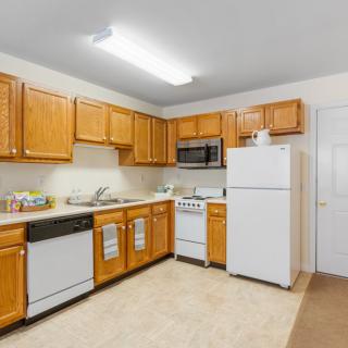 A spacious kitchen with wooden cabinets and white appliances, including a refrigerator, stove, microwave, and dishwasher.