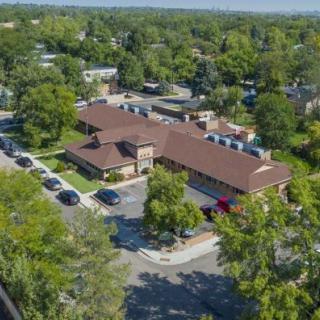 Aerial view of a suburban building surrounded by trees and a parking lot.