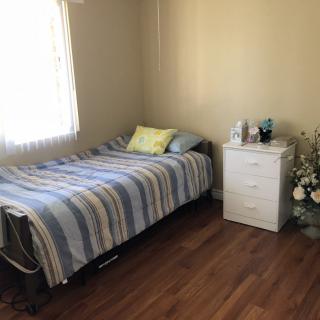 A simple and tidy bedroom with a single bed and nightstand.