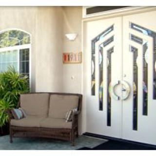 A stylish front porch featuring a unique patterned double door with a cozy seating area and decorative plants.