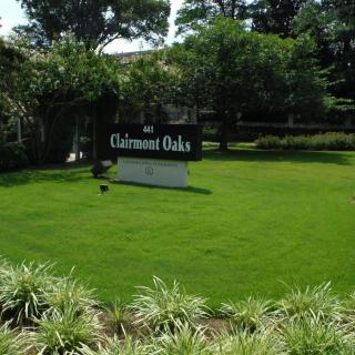 A well-maintained lawn with a sign reading 'Chatmont Oaks' surrounded by lush greenery and trees.