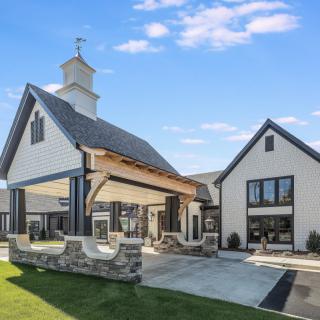 A modern house with a sleek design, featuring stone accents and a spacious outdoor area under a clear blue sky.