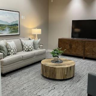 A cozy living room with a sofa, round coffee table, and a large television.