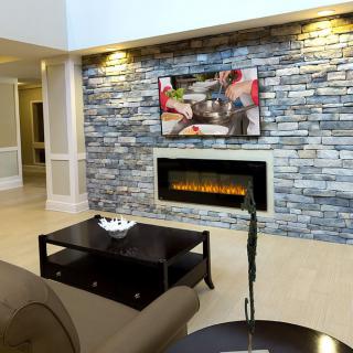 A modern living room with a stone wall featuring a fireplace and mounted television.