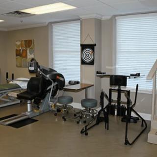 A rehabilitation room equipped with various therapy devices and a dartboard for therapeutic exercises.