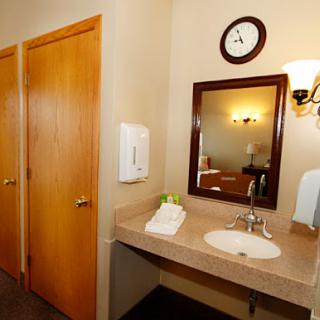 A clean and tidy bathroom featuring a sink, mirror, and wooden doors.