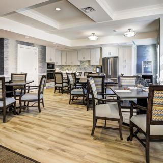 A modern dining area with neatly arranged tables and chairs, adjacent to a kitchen.