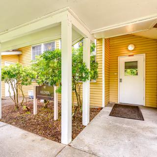 Entrance to a yellow building with a covered walkway and surrounding greenery.