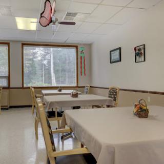 A minimalist dining room with neatly arranged tables and a bright window.