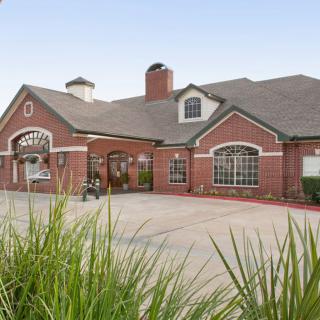 A charming red brick building with a landscaped driveway and traditional architectural features.