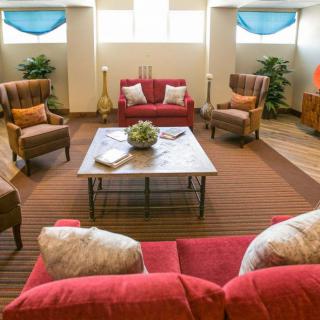 A cozy living room with a red sofa, armchairs, and a wooden coffee table.