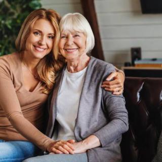 A mother and daughter sitting together on a couch, sharing a warm hug and smile.