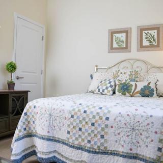 A cozy bedroom with a patterned quilt, decorative pillows, and wall art above the bed.