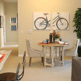 A cozy dining room with a round table, paired chairs, and bicycle-themed artwork on the wall.