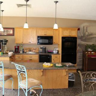 A modern kitchen interior with wooden cabinets, appliances, and a central island with decorative chairs.
