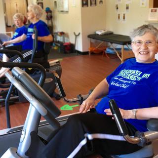 A senior woman exercising on a treadmill in a gym, smiling and enjoying her workout.