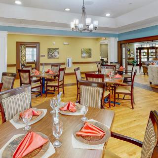 A neatly set dining area with tables and chairs, featuring red napkins and elegant decor.