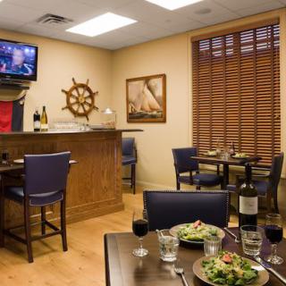 A cozy restaurant interior with a nautical theme, featuring a small bar and tables set for dining.