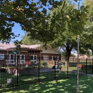 A suburban house with a fenced yard on a sunny day.