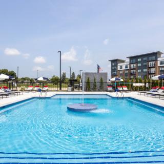 An outdoor swimming pool surrounded by apartment buildings on a sunny day.