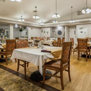 A well-lit dining room with neatly arranged tables and chairs, featuring cozy decor.