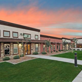 Modern residential housing with a landscaped lawn under a sunset sky.