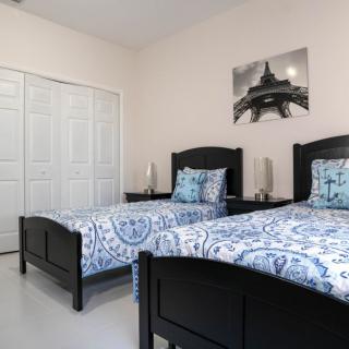 A modern bedroom with twin black framed beds adorned with blue patterned bedding, complemented by a monochrome artwork on the wall.