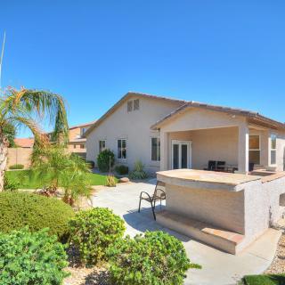A sunny view of a house with a landscaped backyard and patio area.