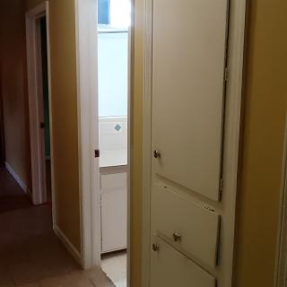 A hallway with a cabinet and partially open door leading to another room.