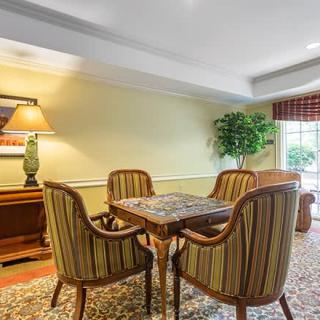 A cozy dining area with a wooden table, striped chairs, and a decorative lamp.