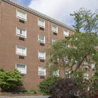 Exterior view of a brick apartment building surrounded by trees.