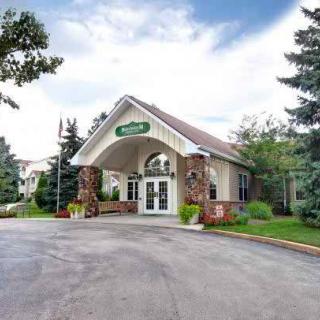 Front view of a building entrance surrounded by trees and landscaping.