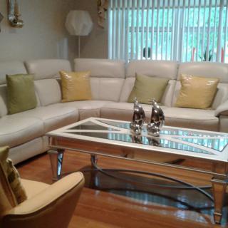 A stylish living room with a sectional sofa, glass coffee table, and decorative elements.