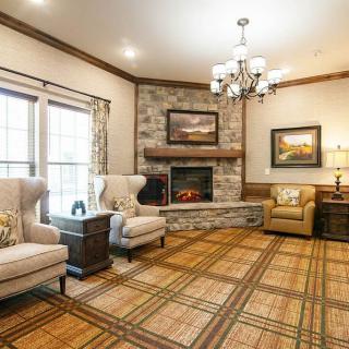A cozy living room featuring a stone fireplace, comfortable armchairs, and a chandelier.