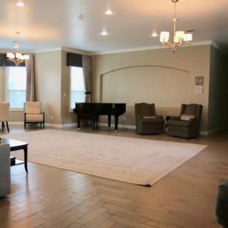 A spacious living room featuring a grand piano, ample seating, and elegant lighting.