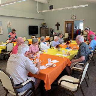 A lively community gathering with seniors enjoying a meal together in a bright and cheerful setting.