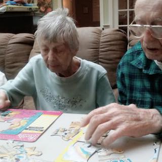 Two elderly individuals engaged in a puzzle activity together.