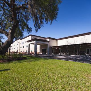 A modern building surrounded by green grass and trees under a clear blue sky.