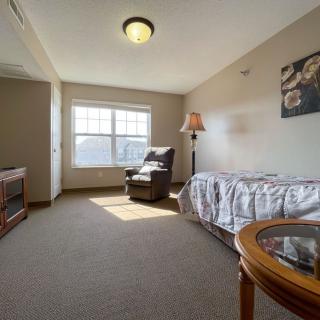 A cozy room with a bed, armchair, and window providing ample natural light.