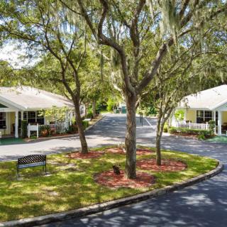 A peaceful residential area with white houses, trees, and a curved driveway.