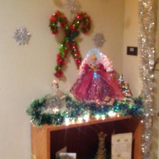 A festive display of Christmas decorations featuring a colorful angel, garlands, and twinkling lights.