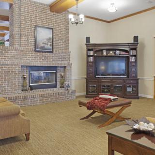 A cozy living room featuring a brick fireplace, television, and comfortable seating.
