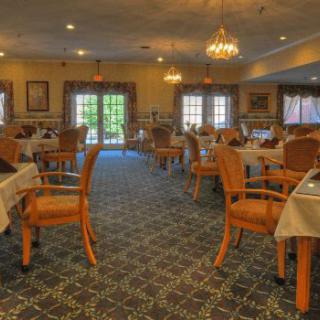 An elegant dining room with neatly arranged tables and chairs, illuminated by chandeliers.