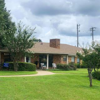 A charming residential home with a well-maintained lawn and a cloudy sky.