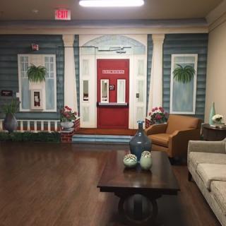A cozy indoor setting featuring a living room with decorative murals resembling an outdoor facade.