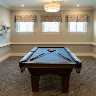 A well-lit game room featuring a pool table with cues neatly arranged.