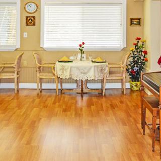 A cozy dining room with a small table set for two, featuring hardwood flooring and decorated with indoor plants and wall art.